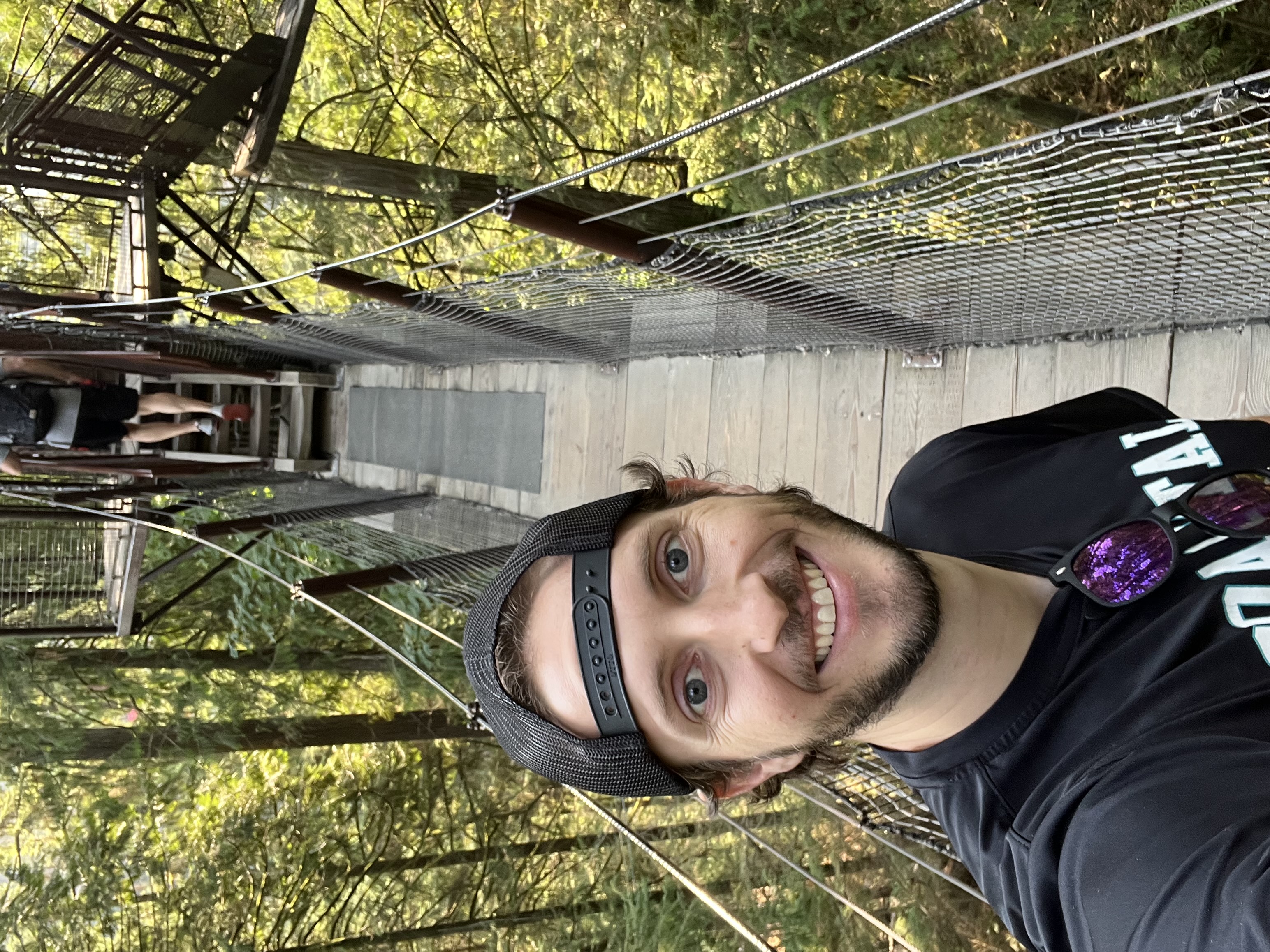 A man takes a selfie on a bridge in a forest canopy